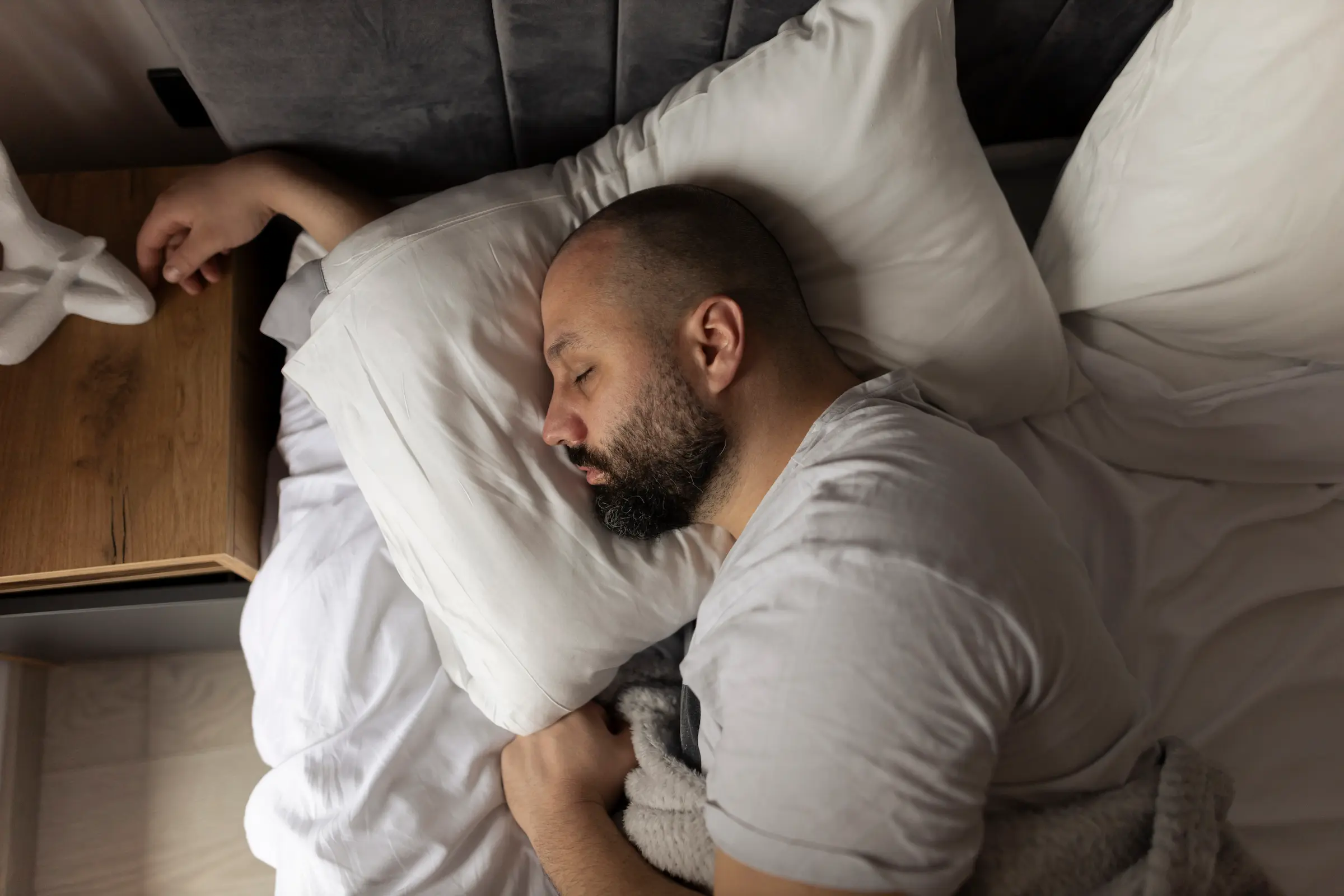 man sover i seng men hånden under puta