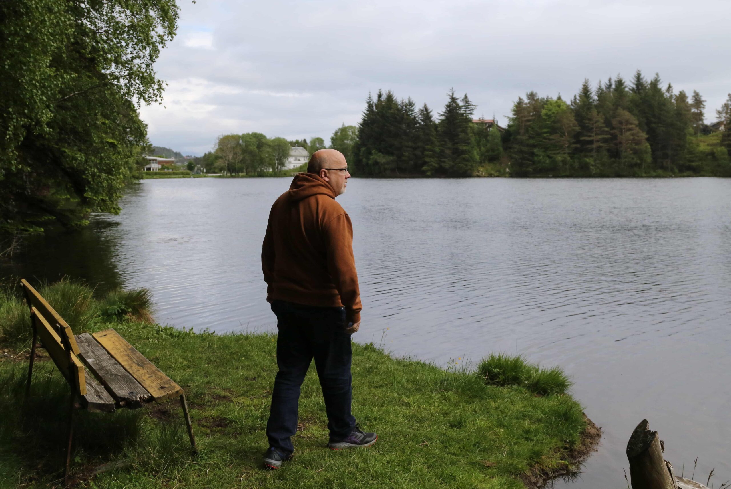 Arne tar et steg fra en benk og ut mot vannkanten. Foto.