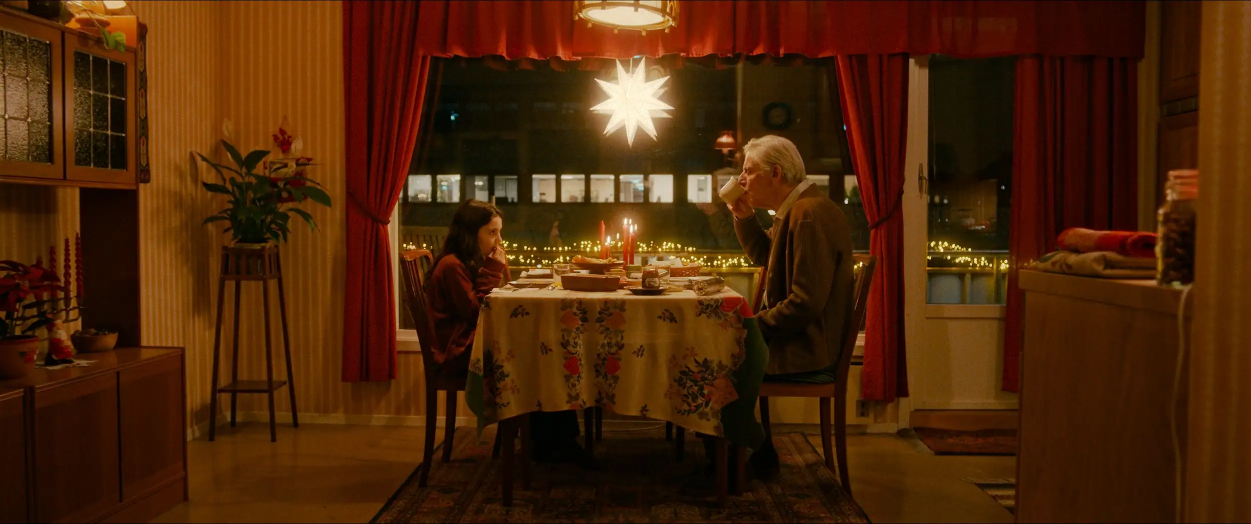 Filmplakat for filmen Stargate. Ronja 10 år sitter ved et julepyntet bord ovenfor Aronsson, som er hennes eldre nabo med grått hår. Det er varmt og koselig lys på kjøkkenet, og i vinduet henger det en adventssjerne og lyser.