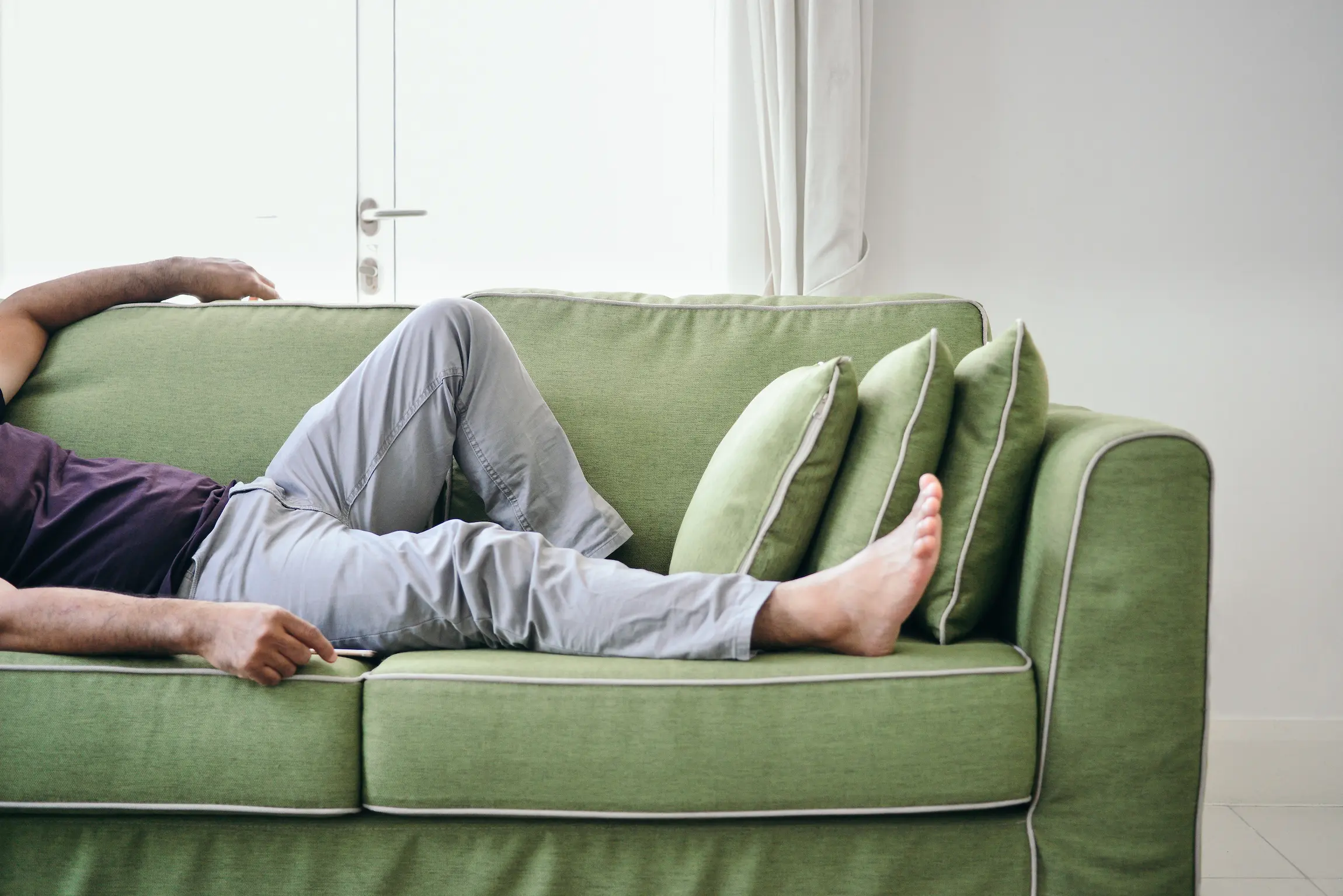 Bilde av nedre del av en mann som ligger henslengt i en sofa
